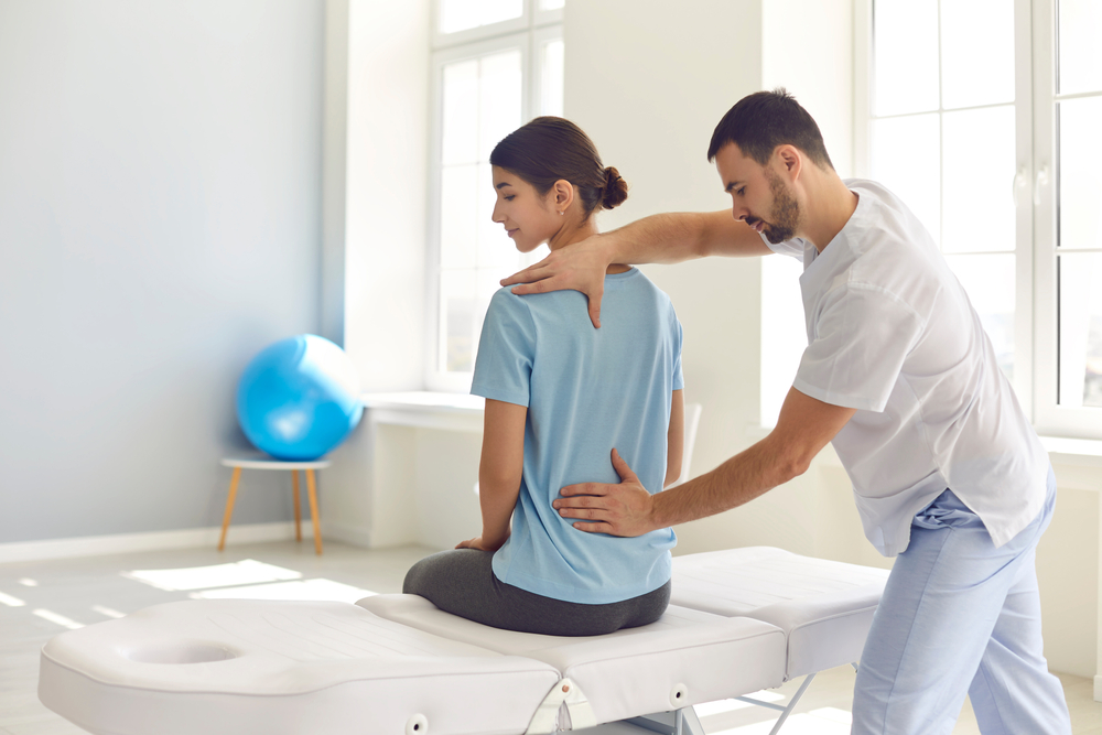 Chiropractor helping female patient with low back pain