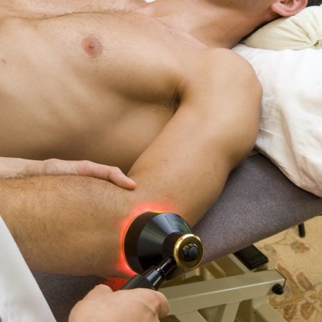 Patient receiving laser therapy treatment on the elbow, aimed at reducing pain and promoting healing