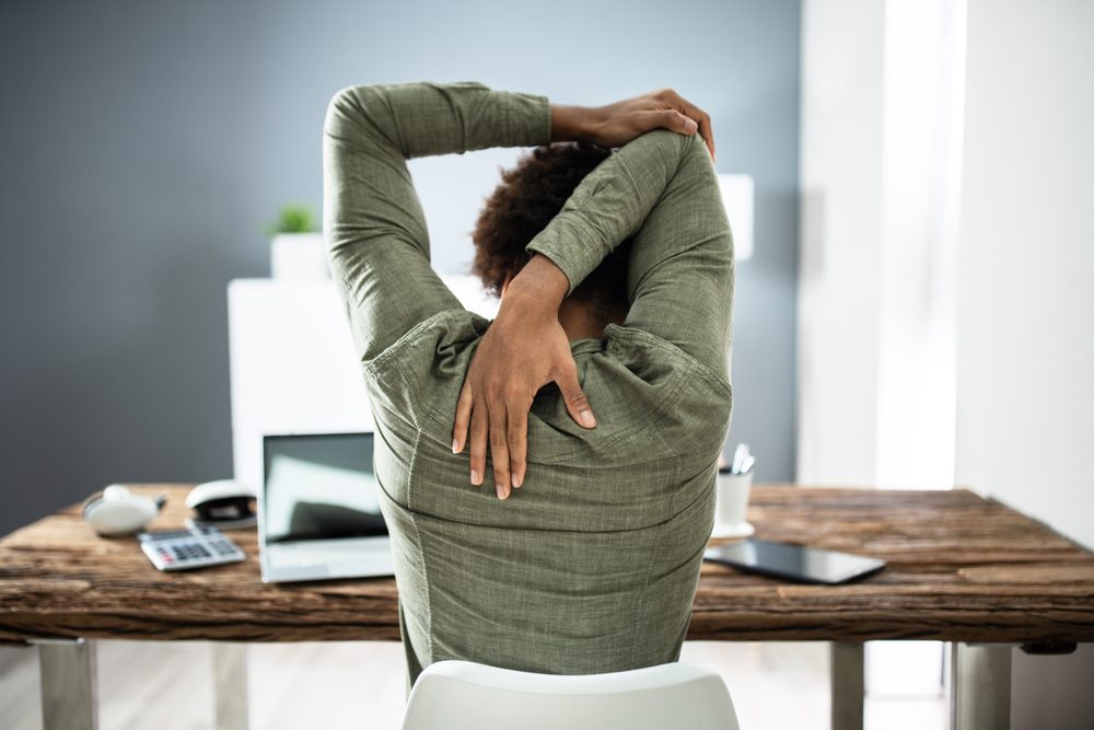 Rear View Of A Businessman Stretching His Arms In Office