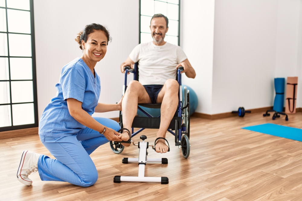 man and woman having rehab session pedaling sitting on wheelchair at physiotherapy clinic