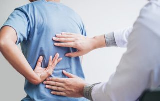 Healthcare professional examining a patient’s lower back during a physical assessment