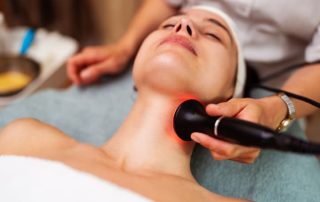 Woman receiving red light therapy treatment on her neck during a professional wellness or skincare session