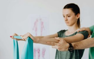 Woman stretching elastic stretch band during examination by physiotherapist