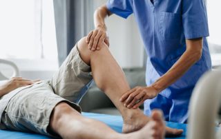 Physiotherapist performing knee joint assessment and rehabilitation therapy on patient’s leg