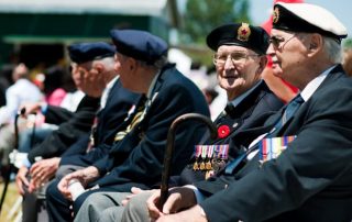 Elderly Canadian veterans wearing medals and poppies during remembrance ceremony outdoors