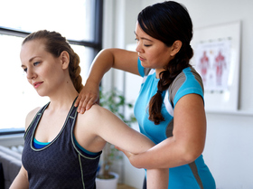Physiotherapist performing shoulder therapy and mobility assessment on a female patient in a clinic
