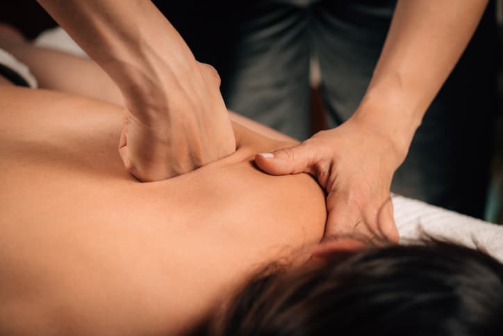 Deep Tissue Massage Therapy for Muscle Tension Relief Chiropractor using red light laser therapy on a patient's lower back for pain relief