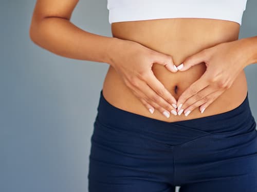 A person forms a heart shape with their hands over their abdomen, symbolizing digestive health, gut wellness, self-care, and overall physical well-being.
