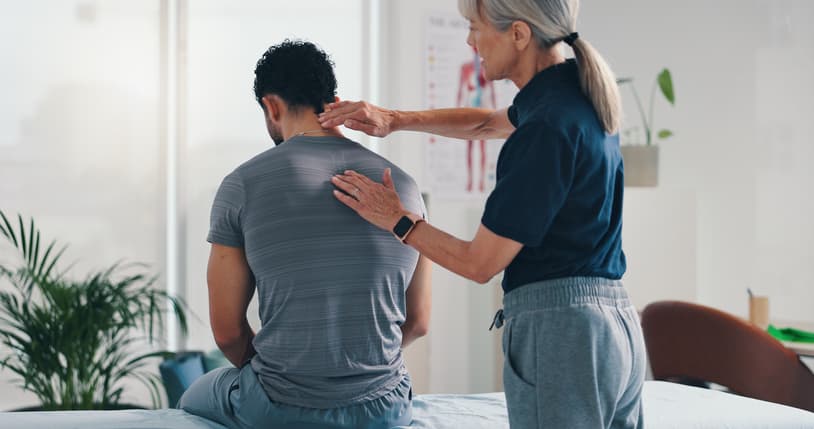 Physical Therapist Assessing Patient’s Posture During Rehabilitation Session Patient with neck pain consulting a chiropractor in an Edmonton clinic