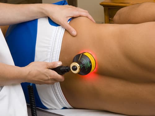 A healthcare professional uses a therapeutic ultrasound device on a patient’s lower back during a physiotherapy session, delivering targeted treatment to help reduce pain, improve circulation, and support soft tissue healing.