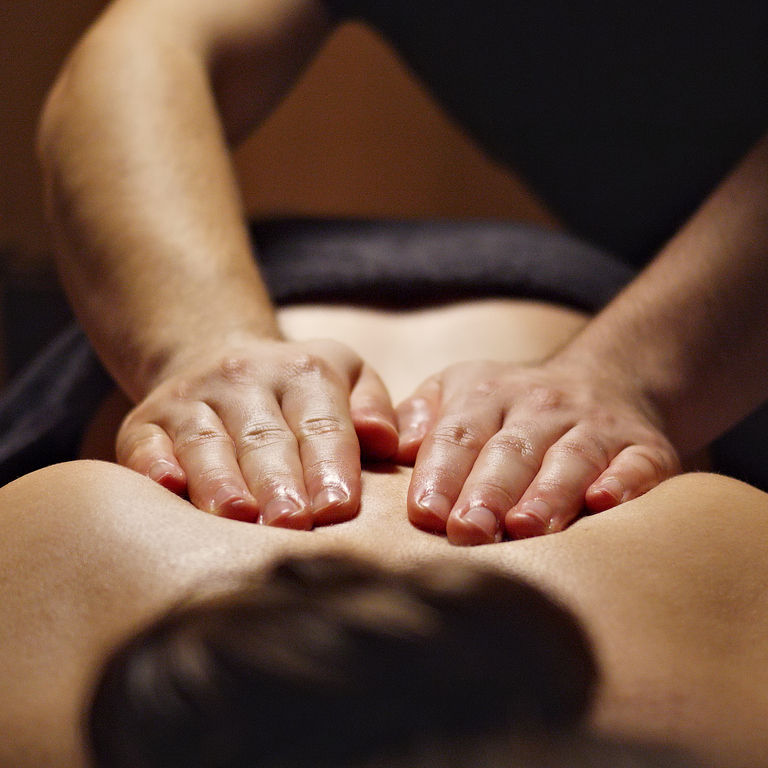 Close-up of a Massage Therapist Providing Stress Relief in a Serene Spa Massage therapist giving a relaxing back massage in a warm spa treatment room.