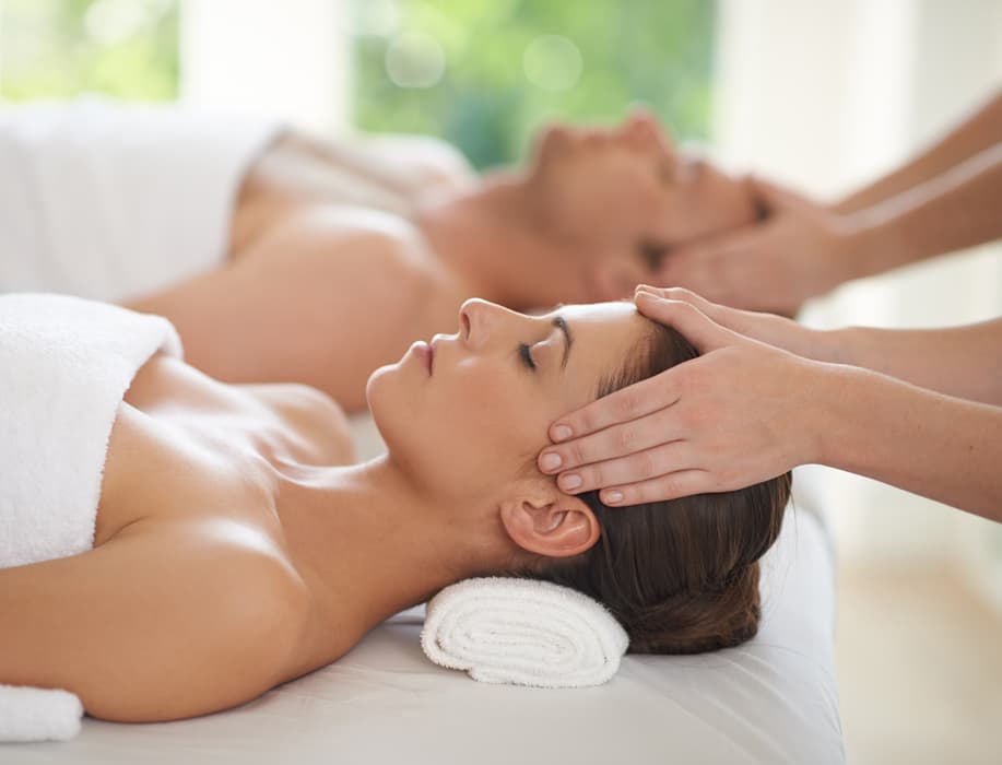 Craniosacral Therapy Treatment Session A therapist performs gentle craniosacral therapy with hands placed on a client's head while two clients relax during treatment. The image highlights gentle manual therapy, stress relief, relaxation, and holistic wellness care.