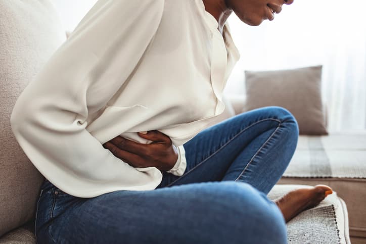 Abdominal Pain and Discomfort Woman holding her lower abdomen while experiencing abdominal pain and discomfort.