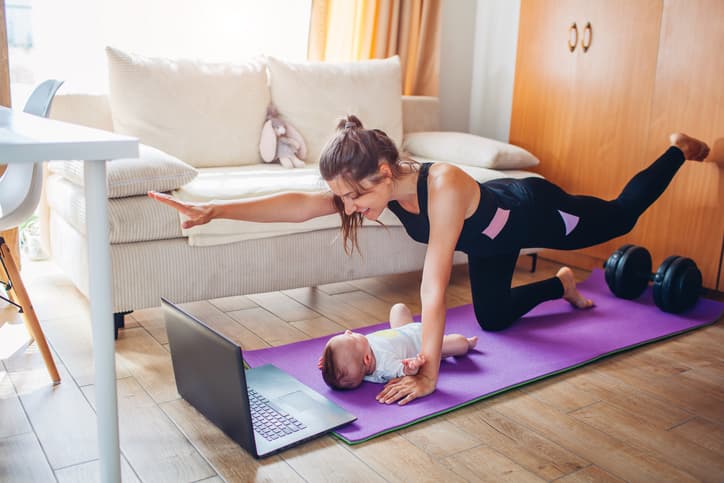 Postpartum Exercise and Recovery Mother exercising at home beside her baby, representing postpartum fitness, core strengthening, and recovery after pregnancy.